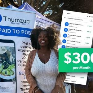 Iman Wims standing in front of a Thumzup promotional banner at an outdoor event, smiling while holding a tote bag.