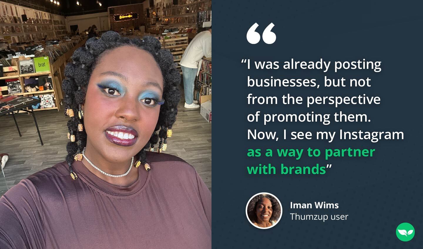 Iman Wims inside a vinyl record store, smiling for a selfie with shelves of records in the background.